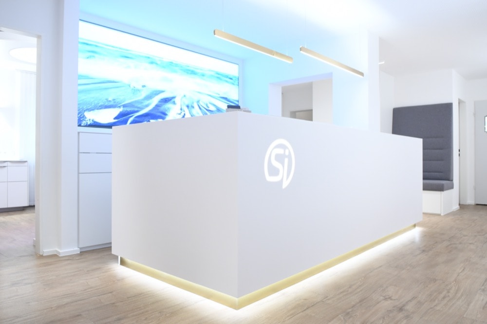 Rezeption / Empfangsbereich mit Sinseder Logo in der Zahnarztpraxis München
